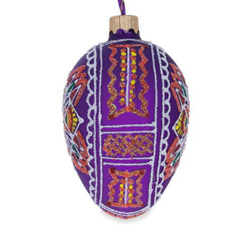 A purple handmade glass Christmas tree egg shaped pendant with a geometrical Ukrainian ornament, embellished with glitter, 2.6 inches