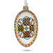 A white handmade glass Christmas tree egg shaped pendant with a Ukrainian traditional ornament, embellished with glitter, 2.6 inches