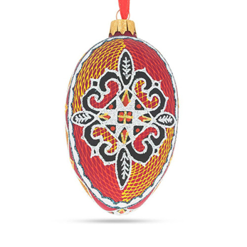 An orange handmade glass Christmas tree egg shaped pendant with a Ukrainian traditional ornament, embellished with glitter "Four leaves", 2.6 inches
