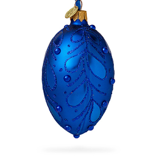 A blue handmade glass Christmas tree egg shaped pendant with a floral ornament, embellished with glitter and pearls, 2.6 inches